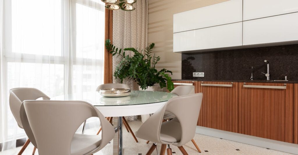 Plate on white round table with stools placed on tiled floor near green potted plant and counter with sink and wooden cupboards in dining room